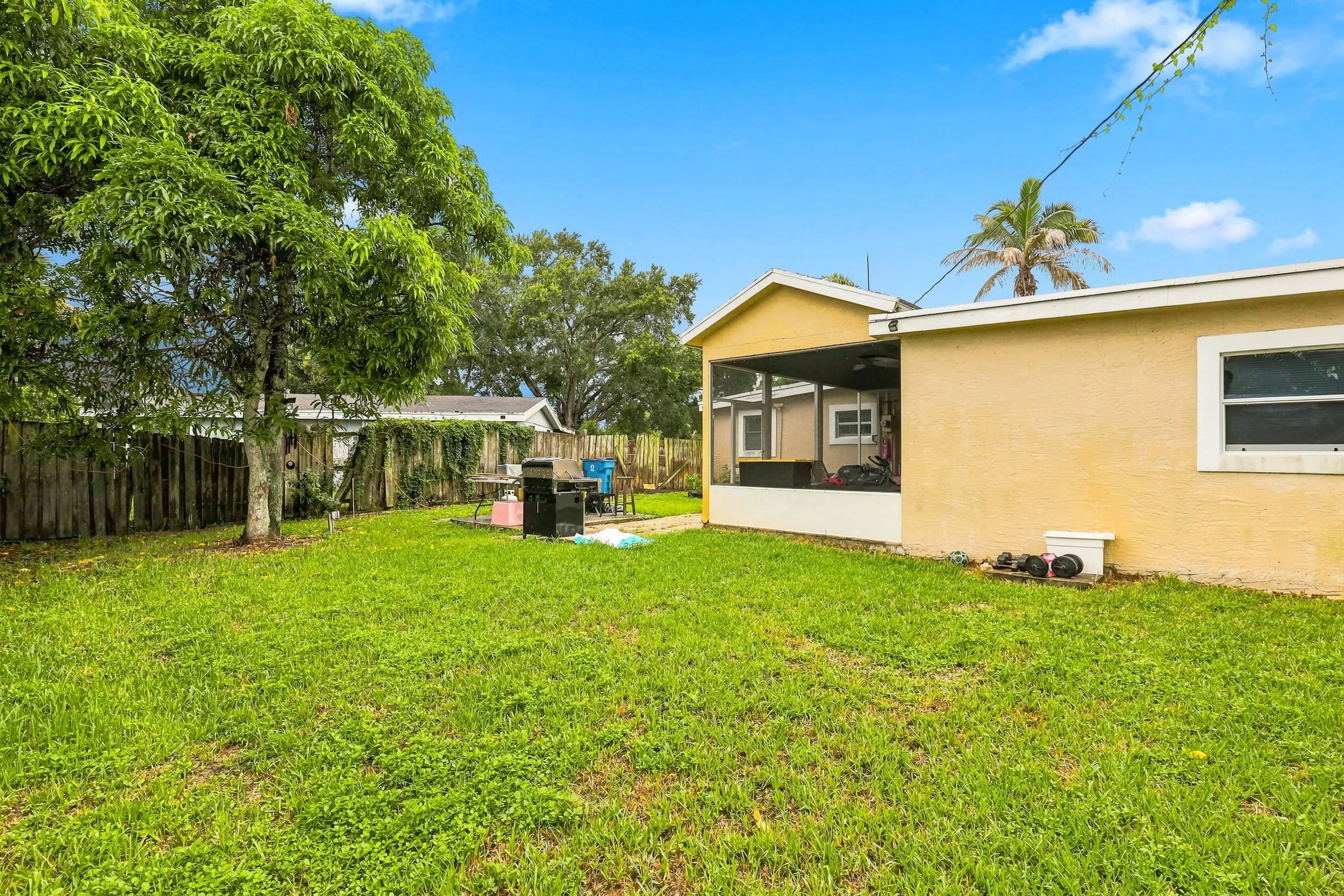 Wide backyard view showcasing the rear of the home, covered patio, and grassy yard.