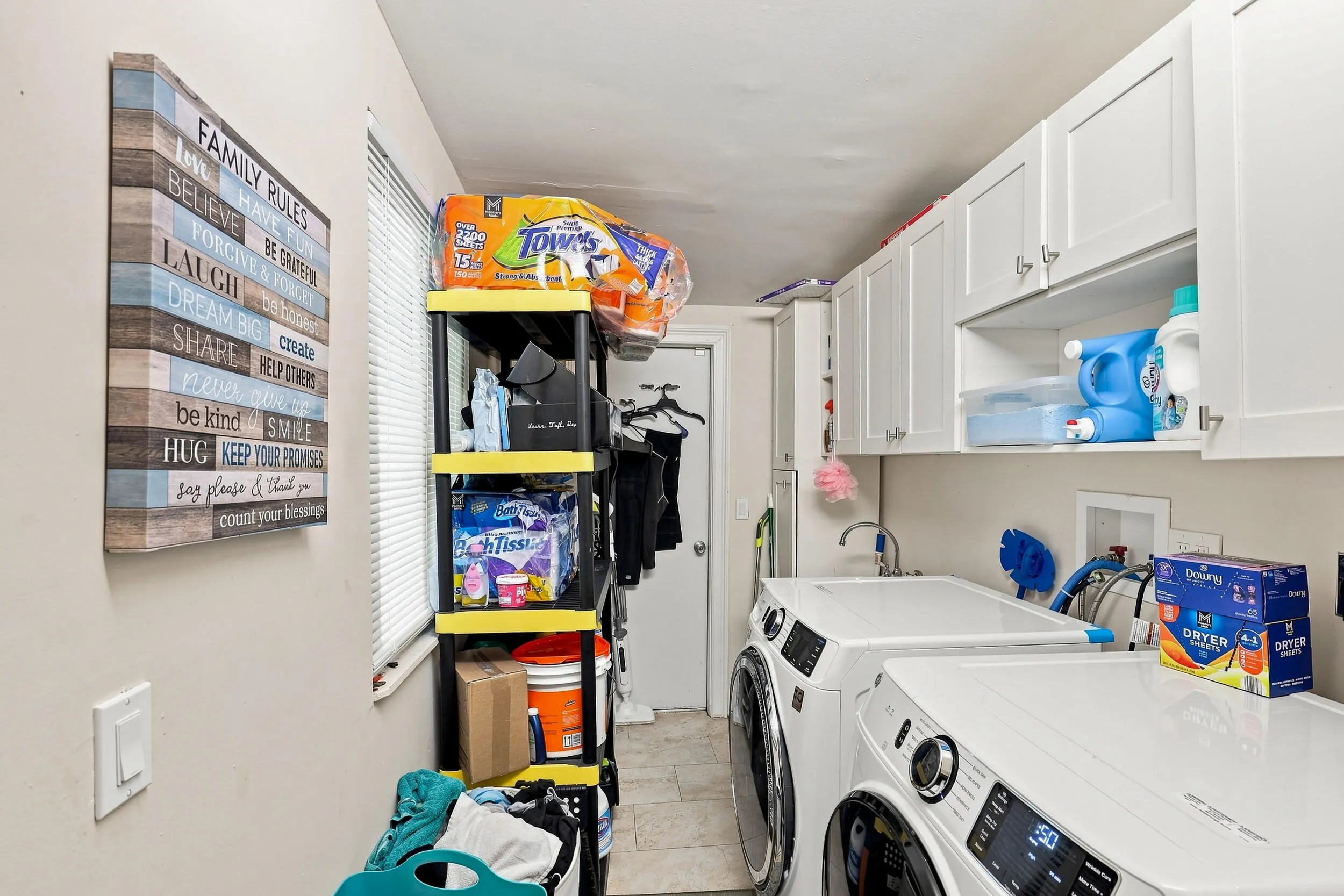 Dedicated laundry room with full-size washer and dryer, cabinetry, and additional storage.