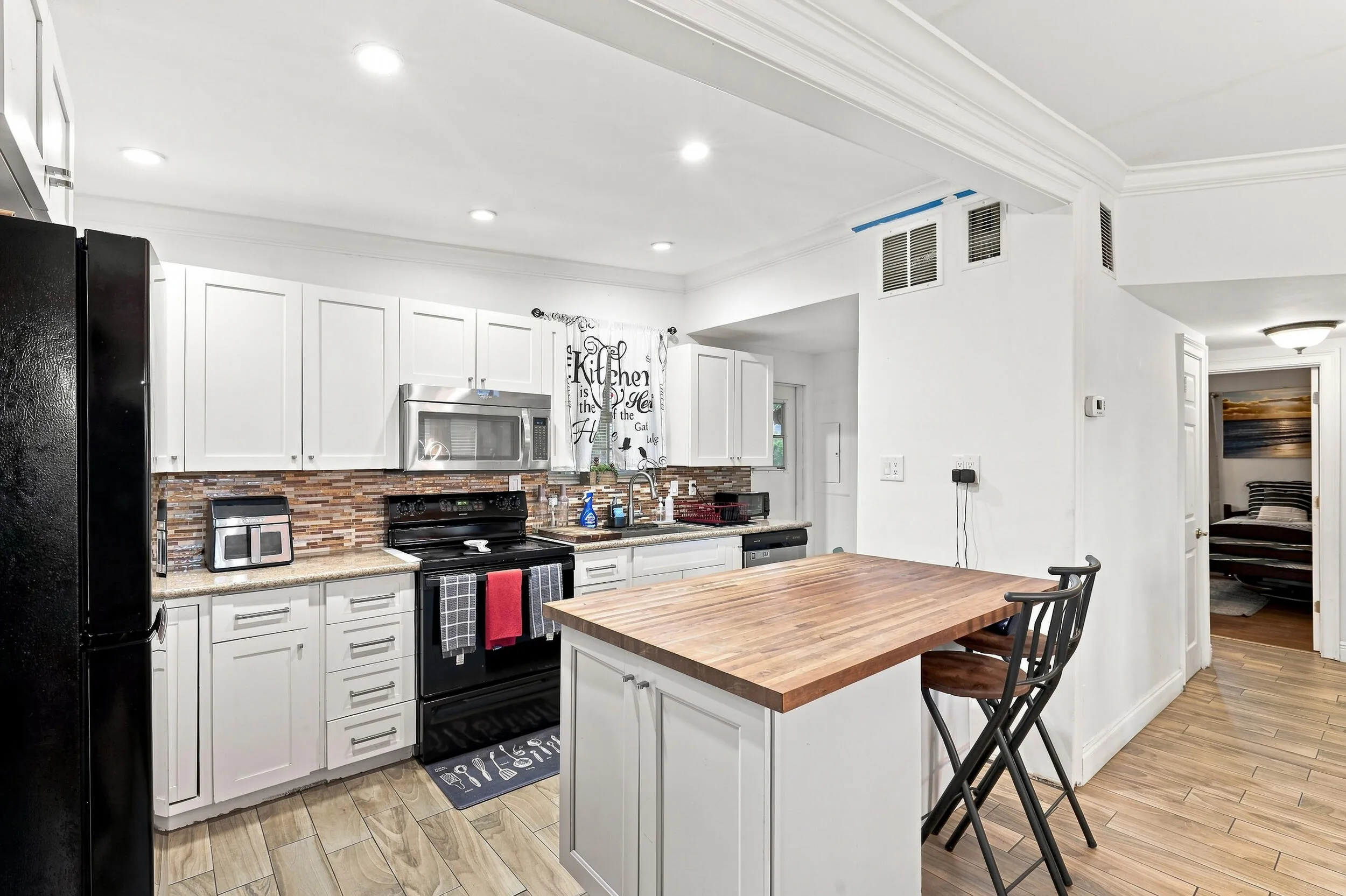 Updated kitchen featuring white cabinetry, ample counter space, and a large center island.