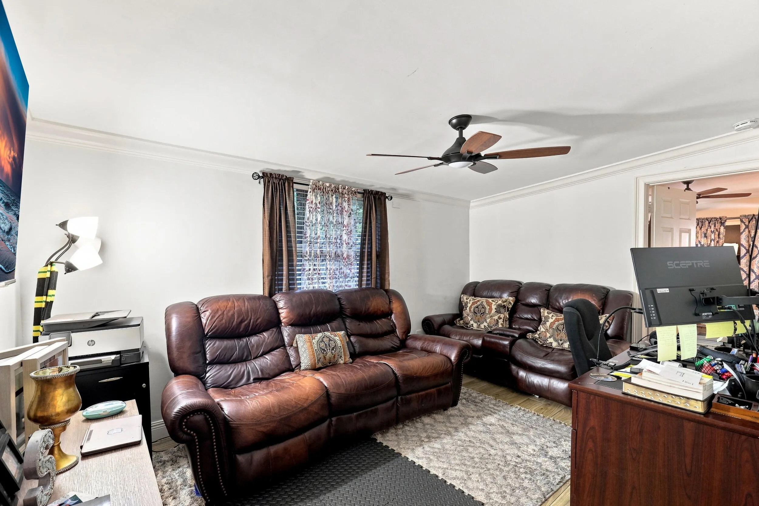 Comfortable living area with ceiling fan, natural light, and plenty of room for seating.