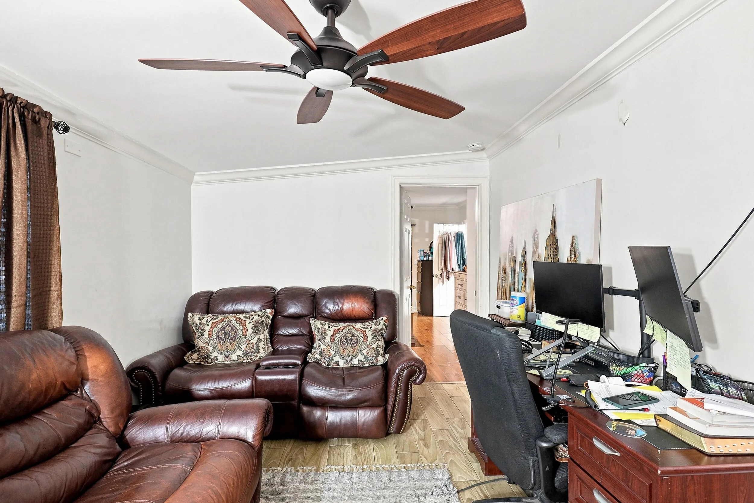 Spacious living room featuring wood-look flooring, ceiling fan, and flexible furniture placement.