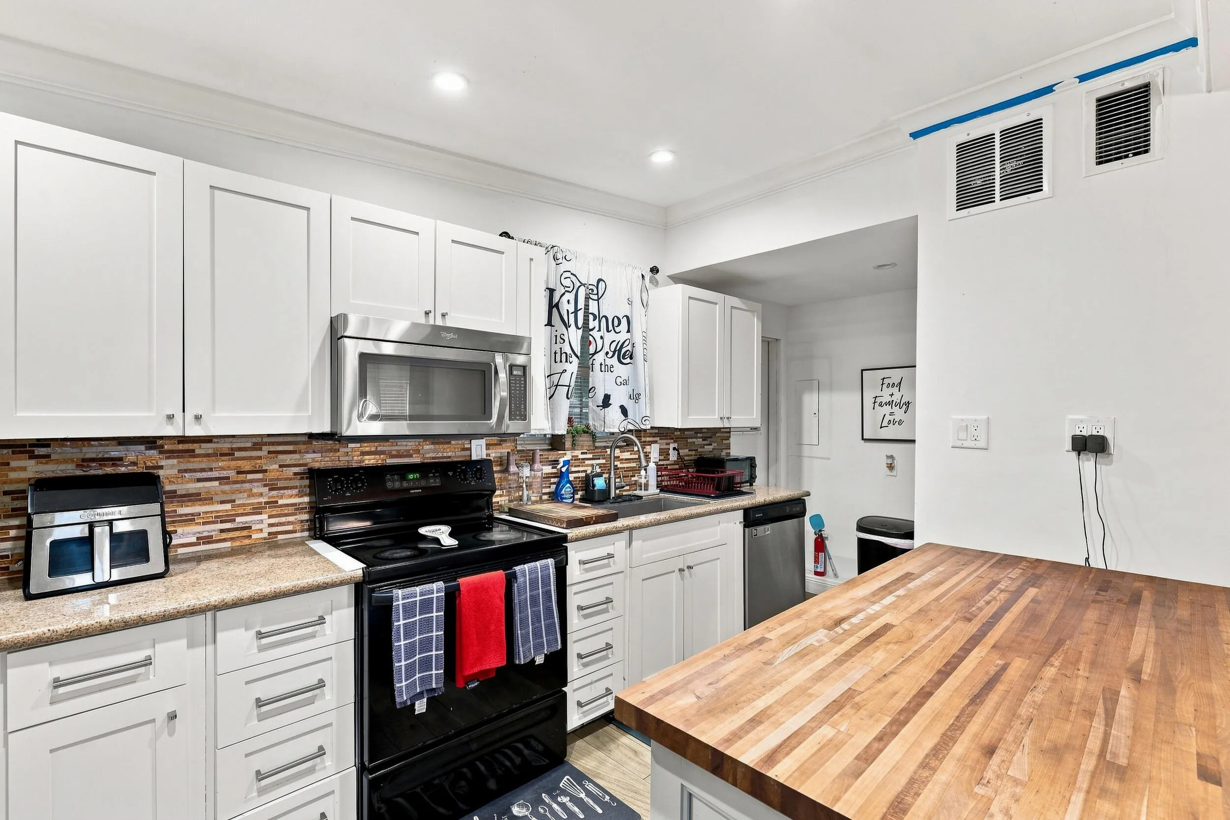 Bright kitchen with white cabinetry, stainless steel appliances, and generous workspace.