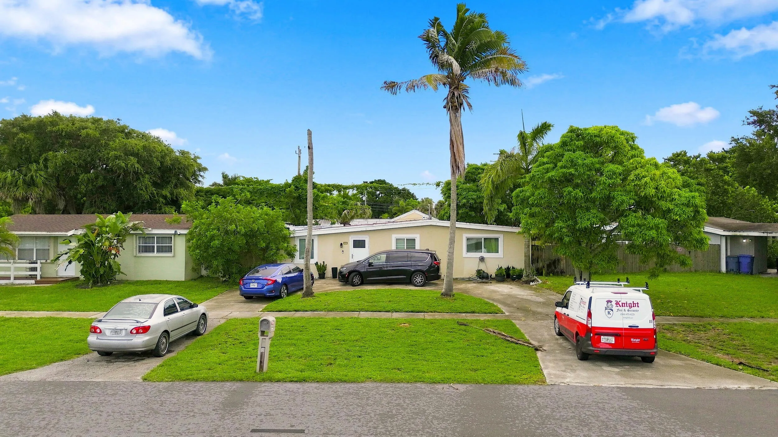 Elevated front view showing the home, spacious front yard, driveway, and residential setting.