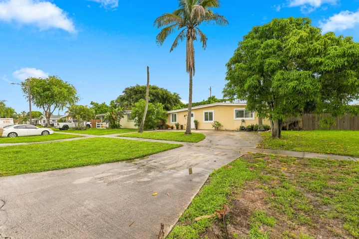 Inviting front view with open green space, mature landscaping, and plenty of room to enjoy the outdoors.