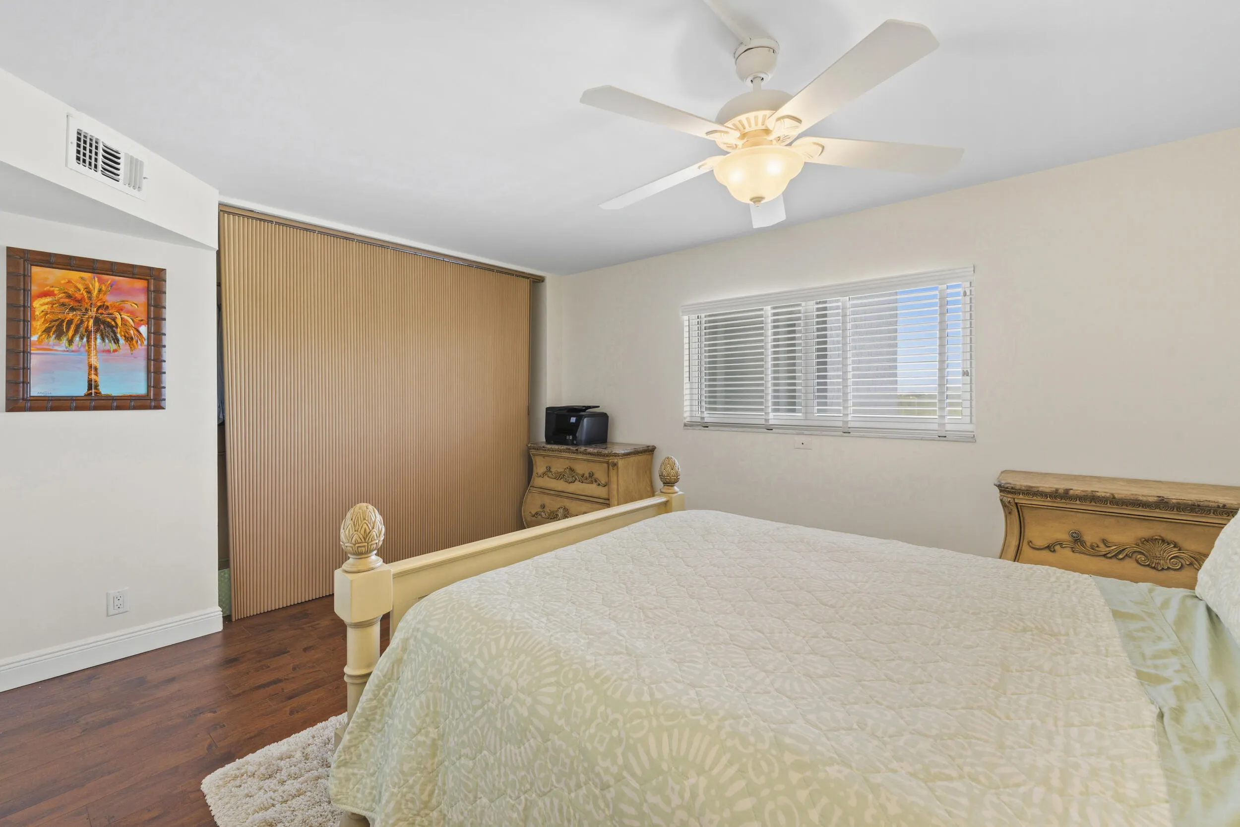 Wood-finish flooring, ceiling fan with integrated lighting, window with horizontal blinds, built-in closet with louvered doors