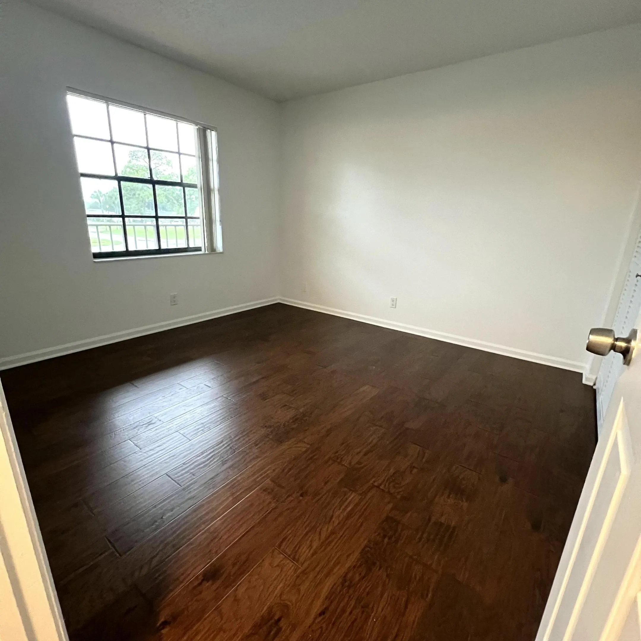 Hardwood-style flooring throughout, white walls, and a multi-pane window
