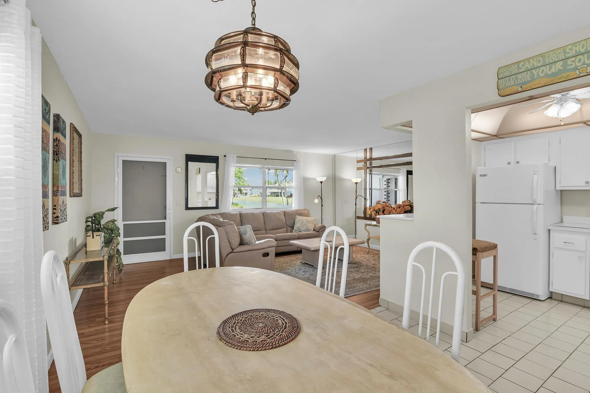 Open-concept living space with a decorative overhead light fixture, a screened door, and a window overlooking a body of water