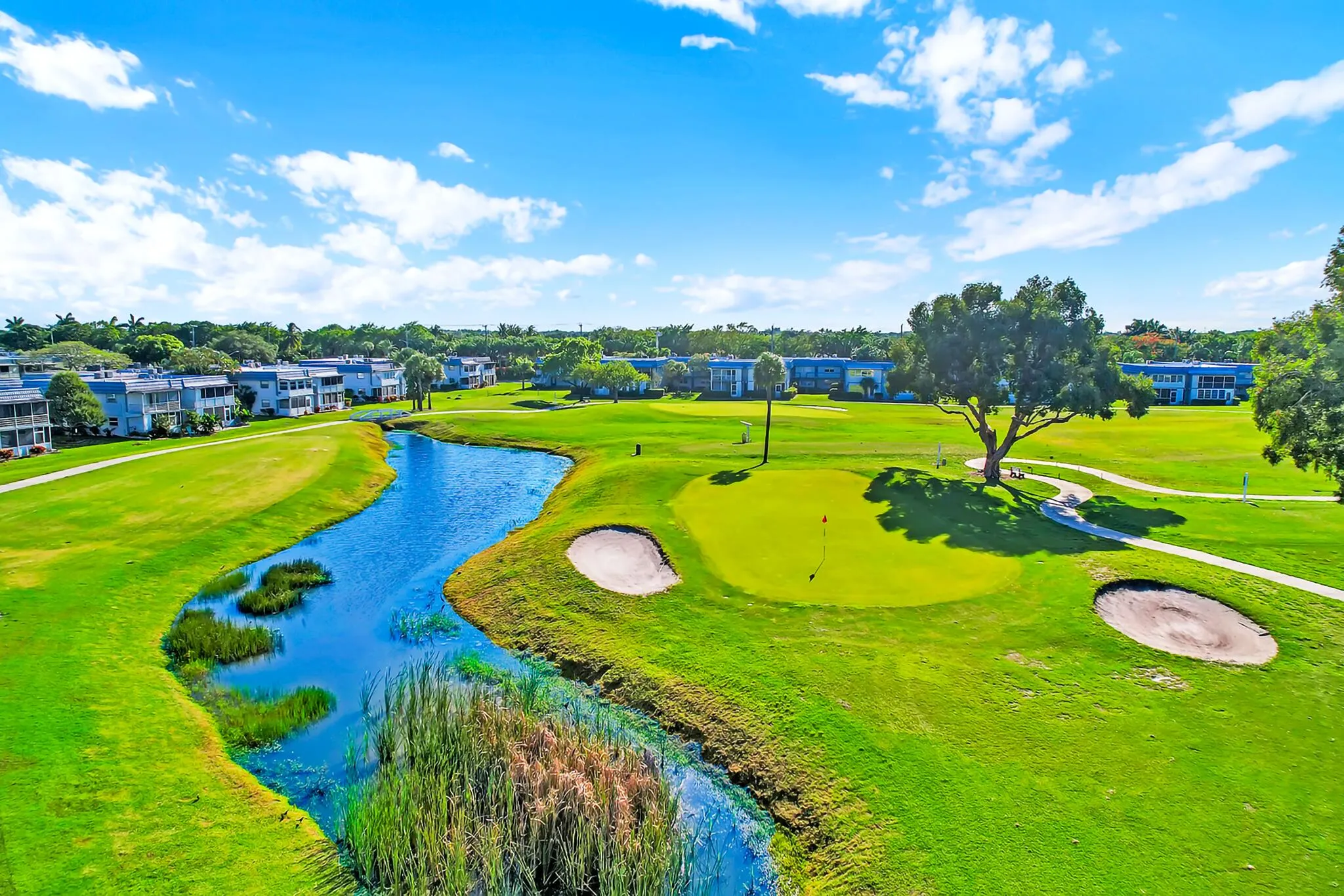 Golf course property featuring a manicured green, sand traps, and a winding water feature