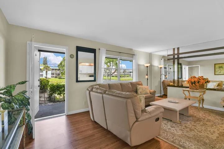 Living area with wood-finish flooring, light neutral wall paint, and multiple windows