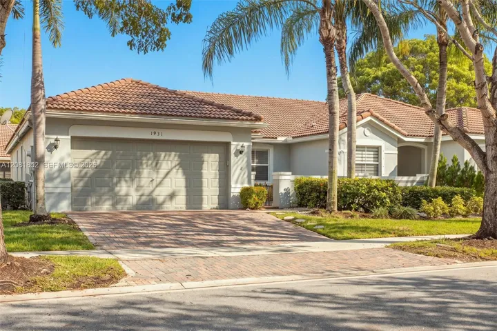 Elegant entry with two-car garage set amid lush tropical landscaping.