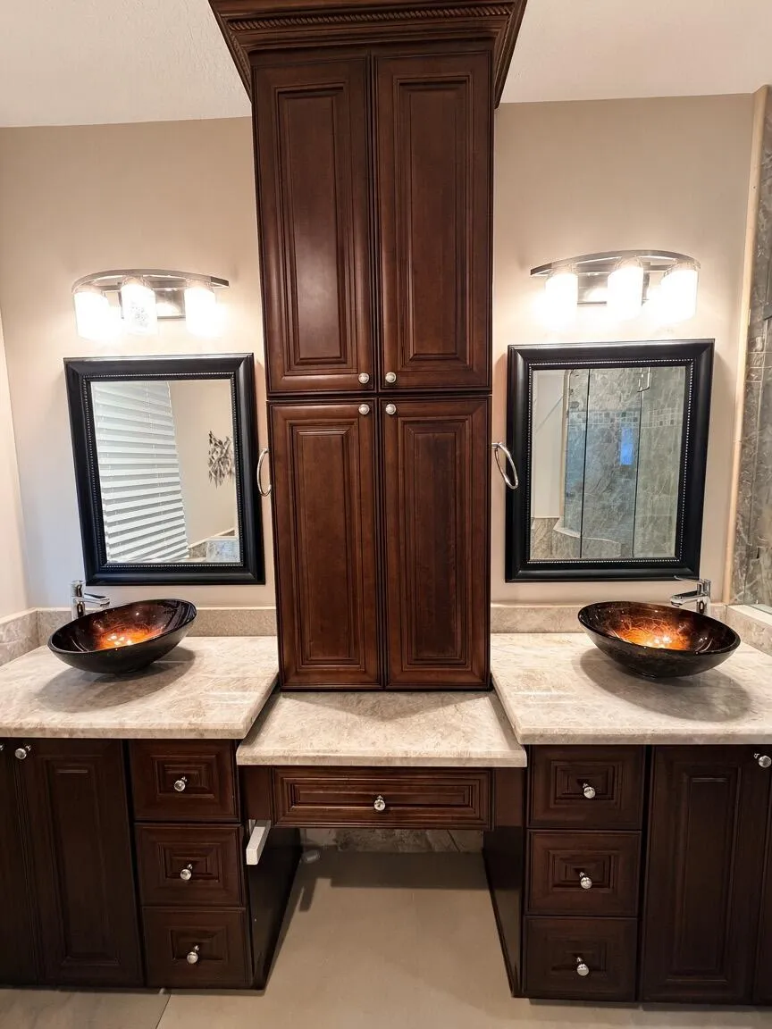 Dual vessel sinks with integrated countertop, dark wood-finish cabinetry, and framed mirrors