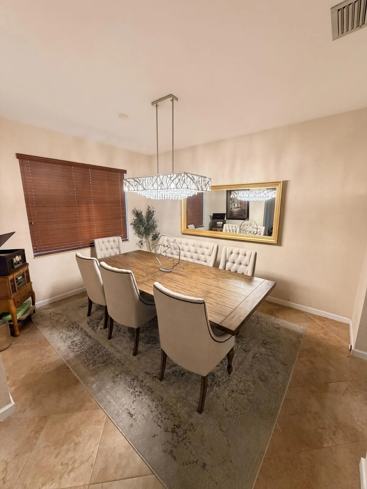 Recessed lighting and a rectangular crystal chandelier illuminate this dining area