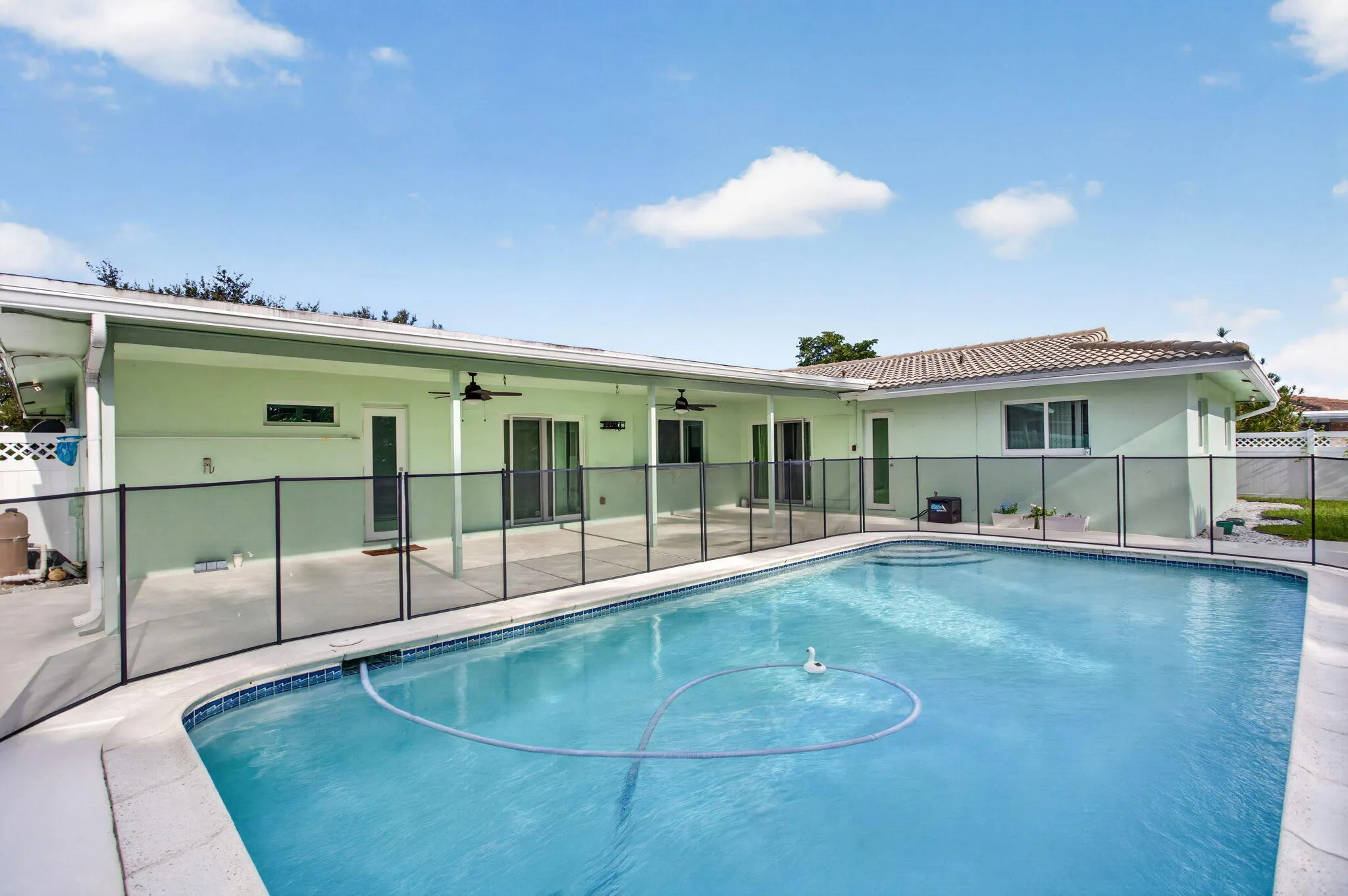 Outdoor swimming pool featuring a safety fence, concrete patio, covered patio area, and sliding glass doors