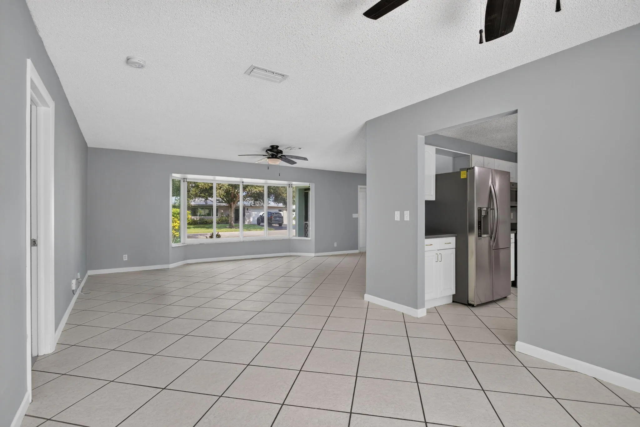 Spacious interior featuring tile flooring, a large bay window, and ceiling fans