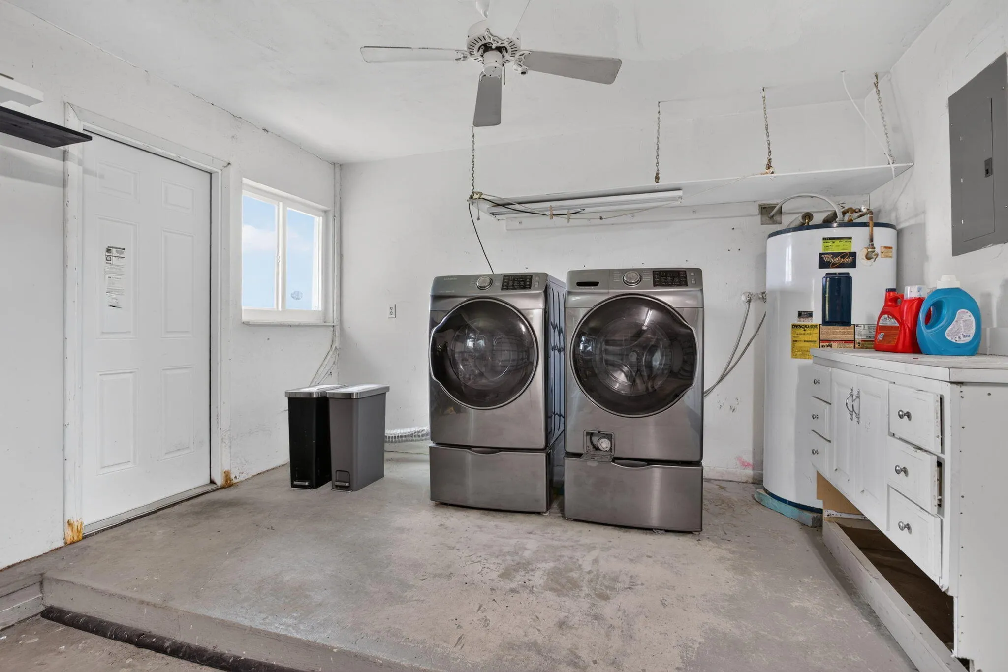 Dedicated utility space with concrete flooring, a single window, and built-in cabinetry featuring a countertop