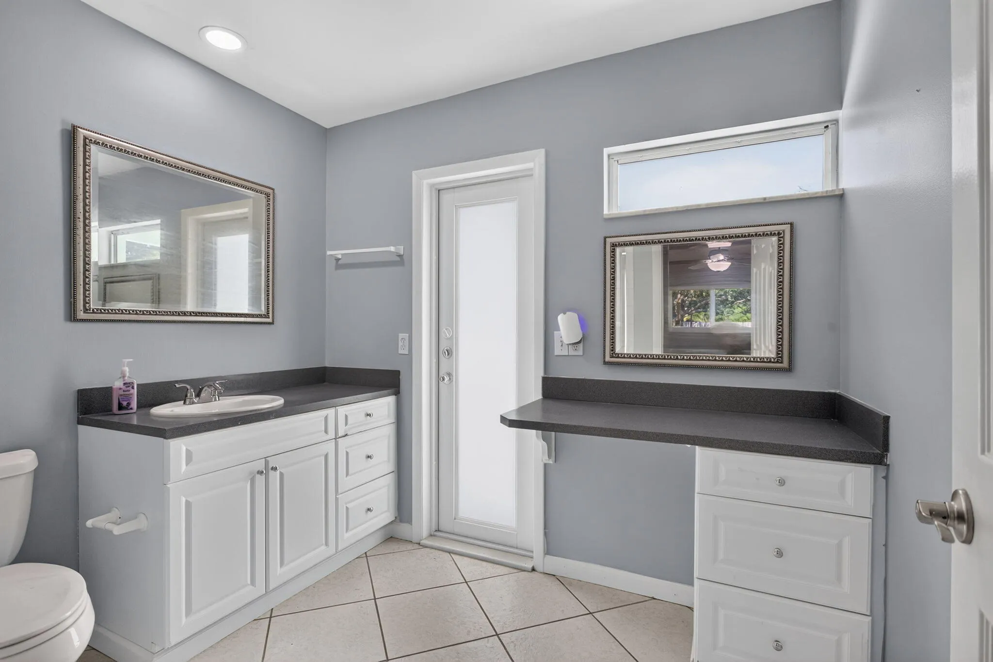 White cabinetry with dark countertops, recessed lighting, and a transom window
