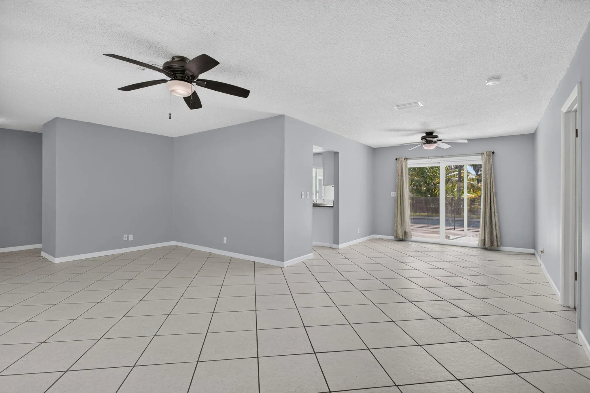 Spacious interior with tile flooring, neutral wall tones, and ceiling fans