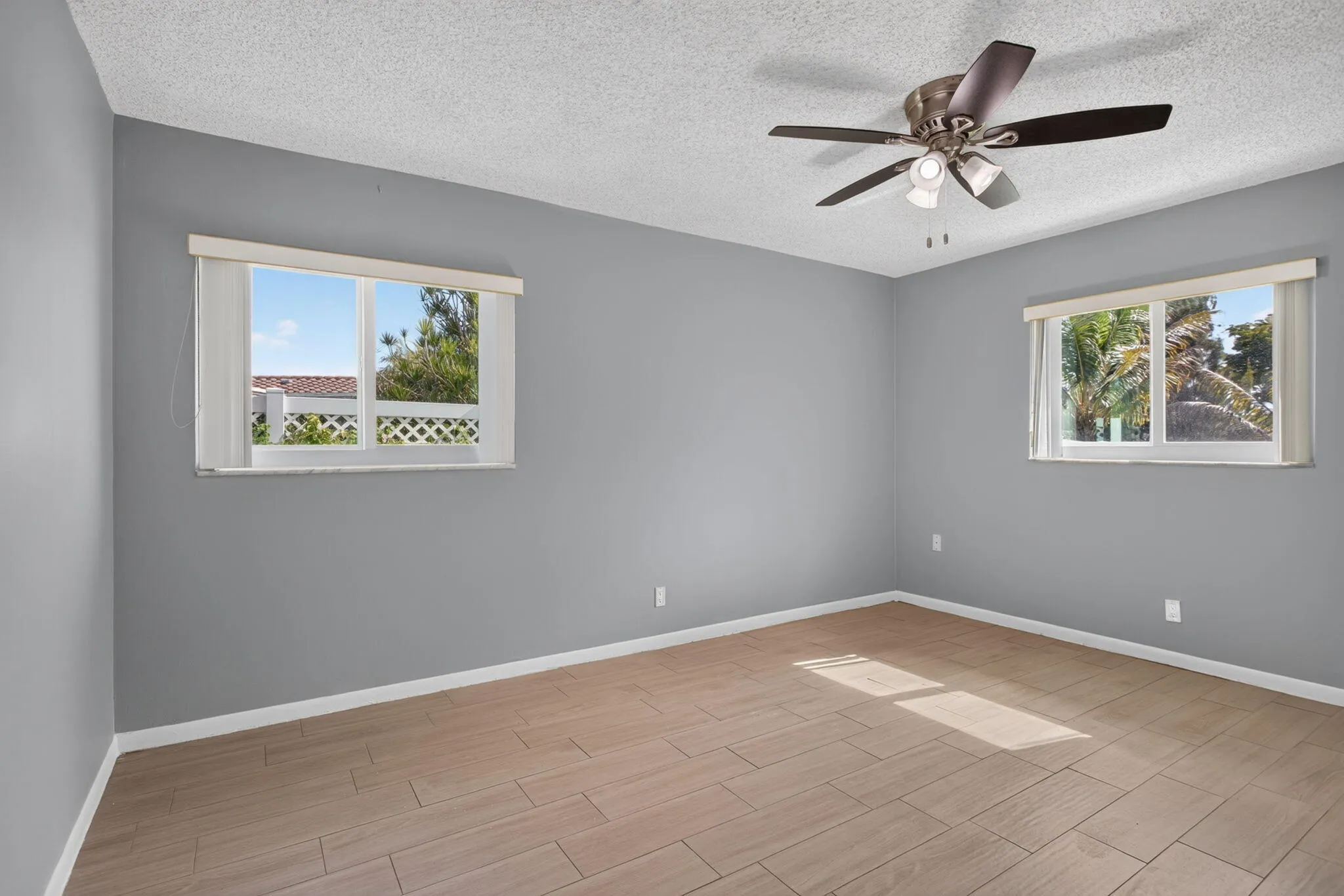 Room with wood-finish flooring, two windows, and a ceiling fan