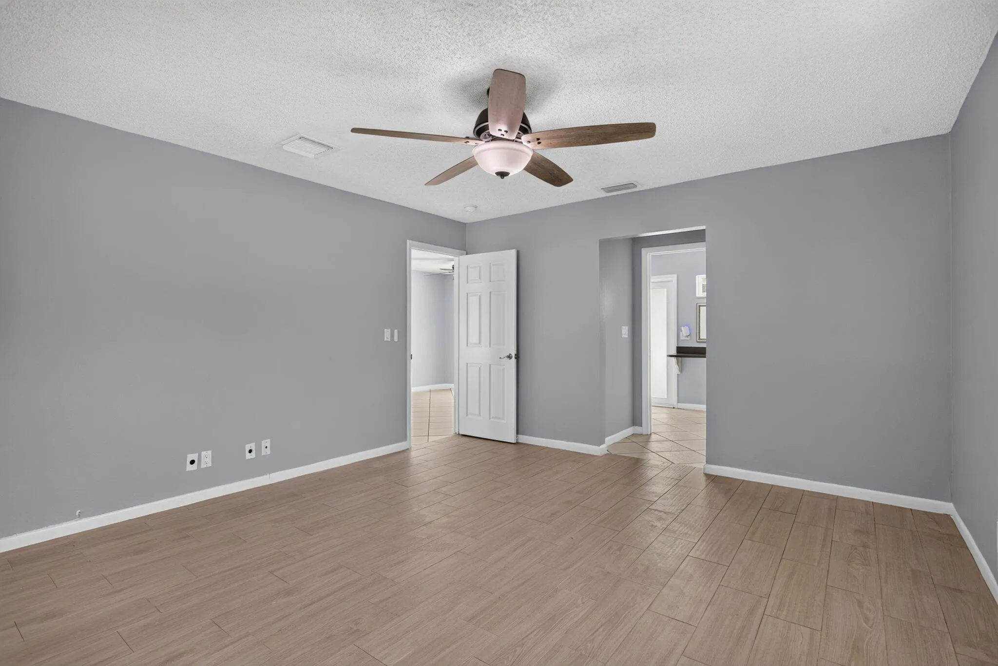 Wood-finish flooring, ceiling fan with integrated lighting, and multiple doorways