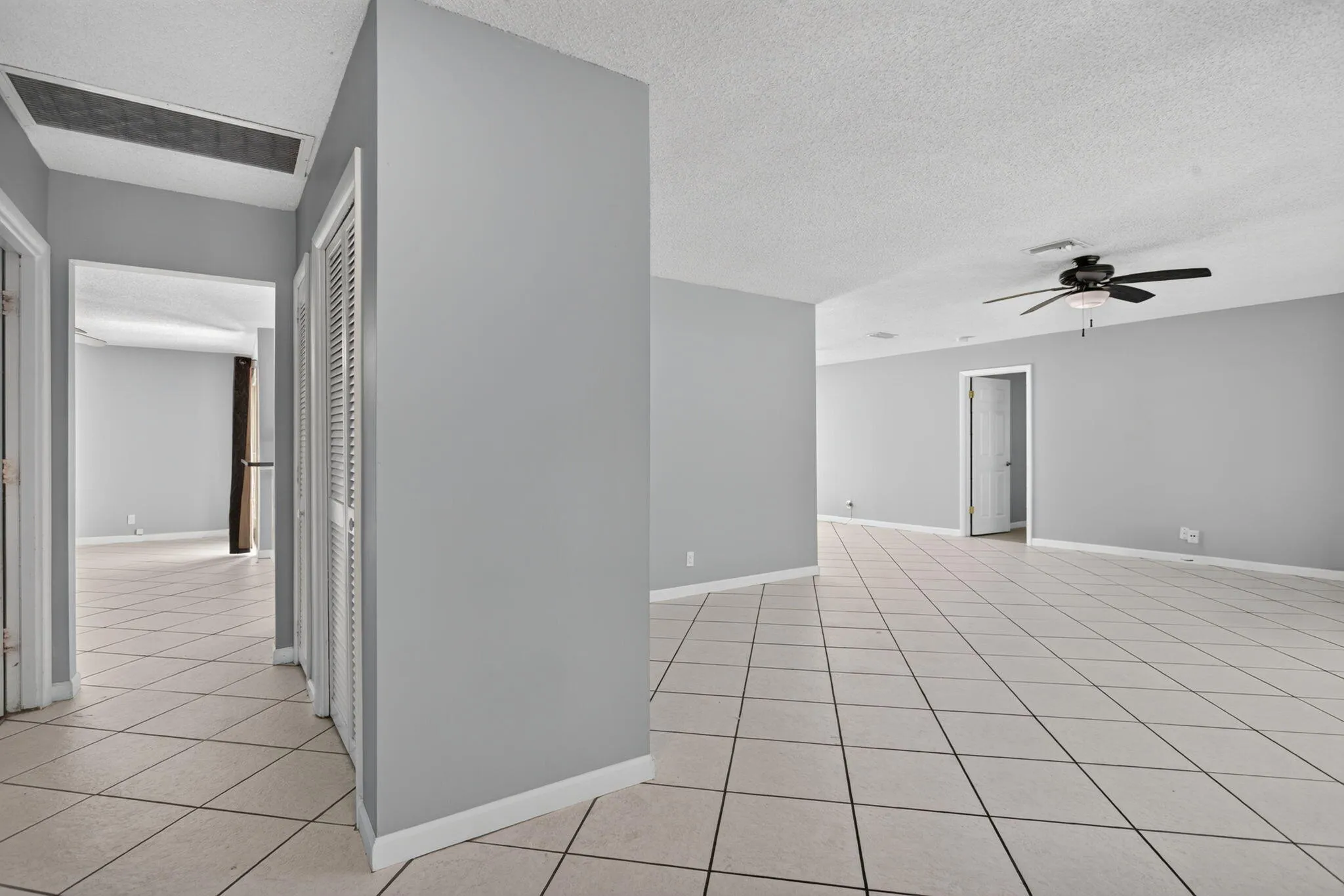 Neutral gray walls, light tile flooring, and a ceiling fan with integrated lighting