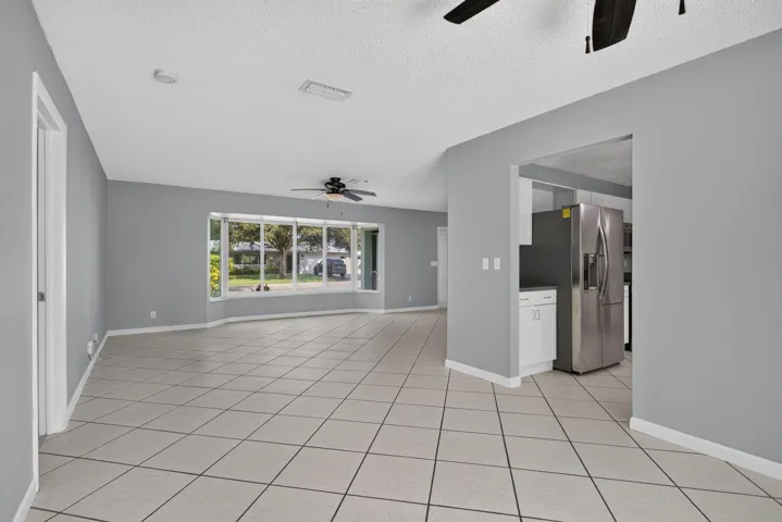 Spacious interior featuring tile flooring, a large bay window, and ceiling fans