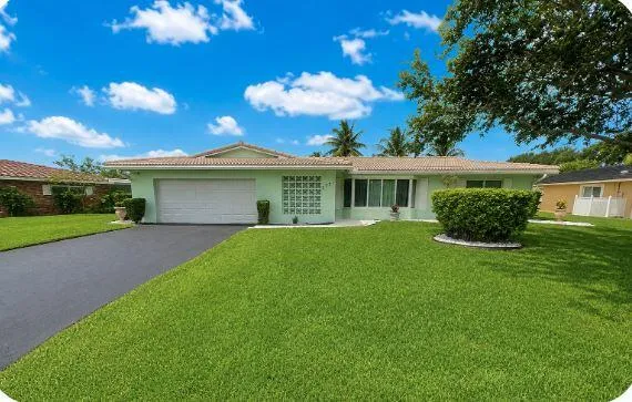 Single-story residence featuring a tile roof, an integrated garage, and a lush front lawn
