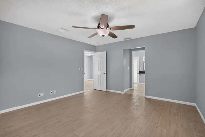 Wood-finish flooring, ceiling fan with integrated lighting, and multiple doorways
