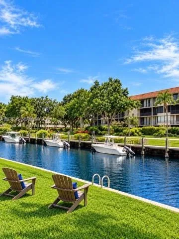 Waterfront canal with deep-water boat slips, concrete seawall, metal ladder, and expansive manicured lawn