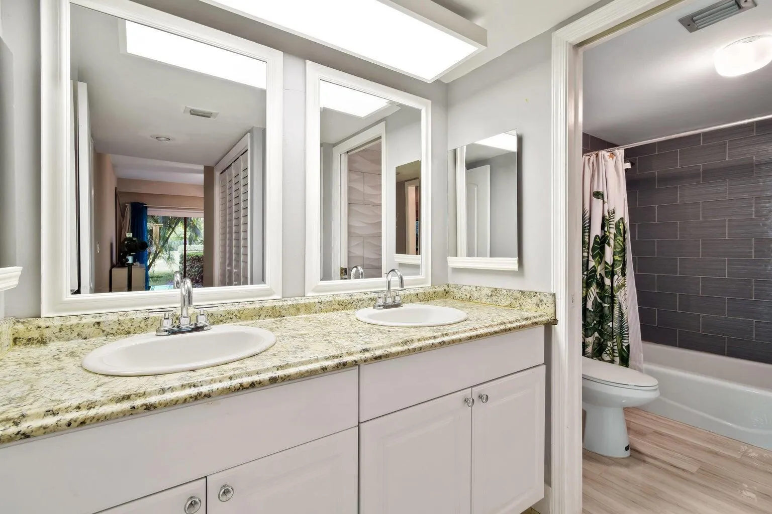 Dual vanity with undermount sinks, granite countertop, and white cabinetry