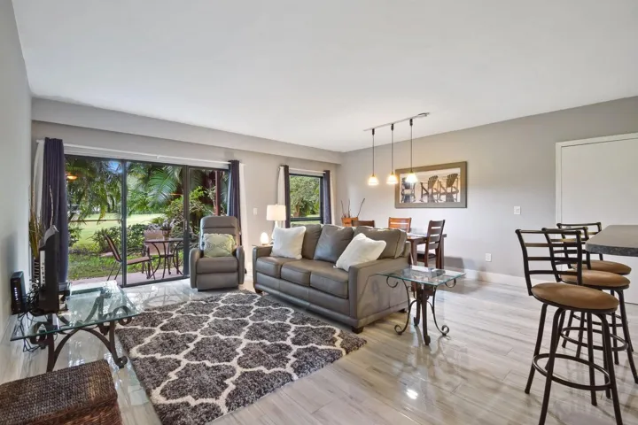 Spacious living area featuring wood-finish flooring, sliding glass doors, and a dining area with pendant lighting