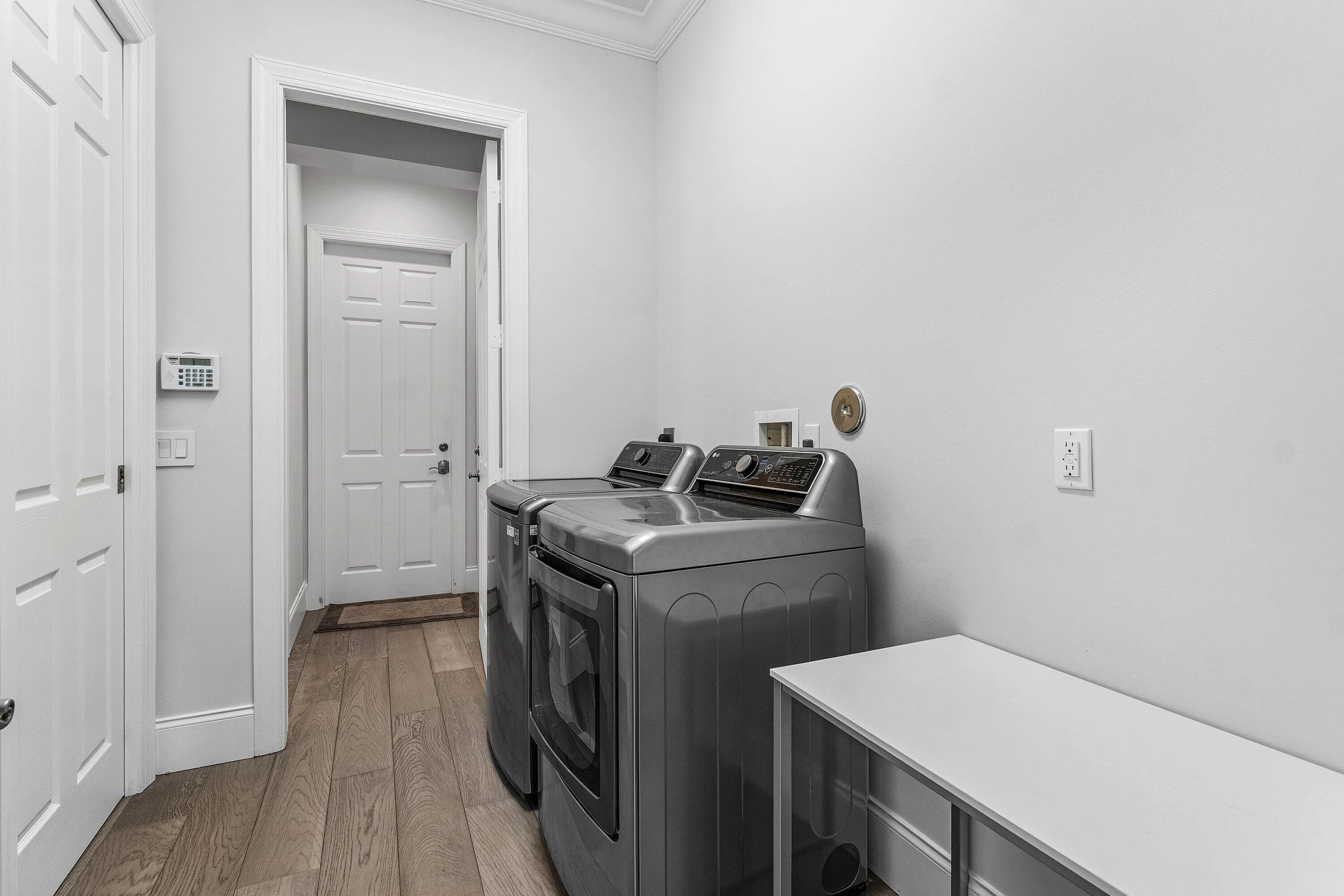 Laundry area featuring wood-finish flooring, white walls, and a built-in folding counter