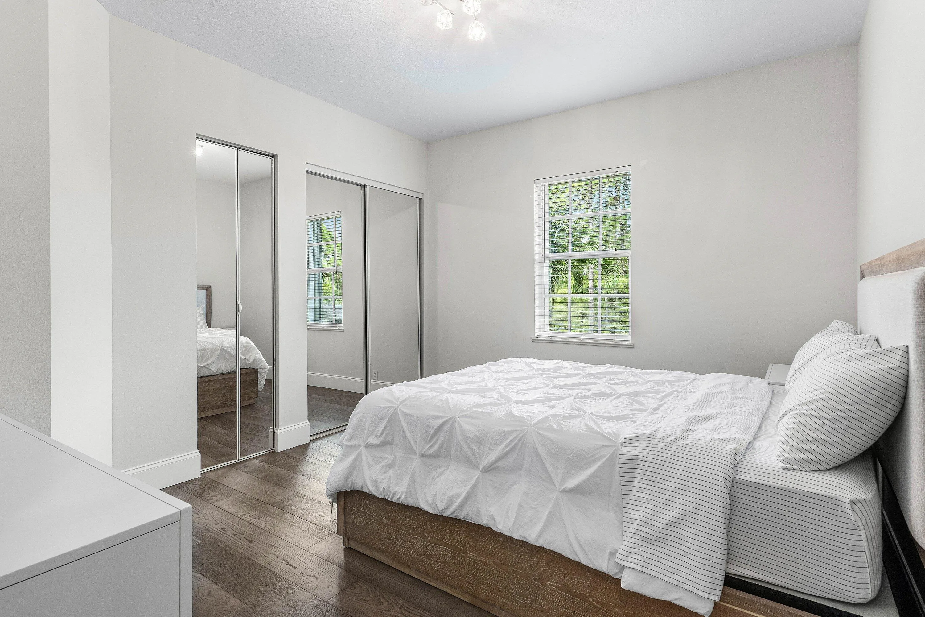 Wood-finish flooring, mirrored sliding closet doors, and a window with natural light