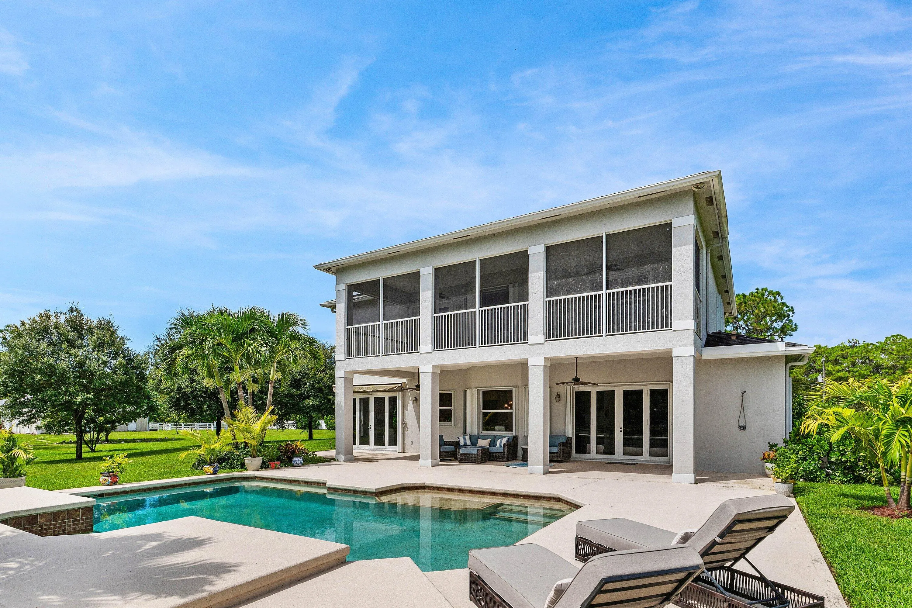 Expansive outdoor area featuring a swimming pool, extended patio, and screened upper balcony