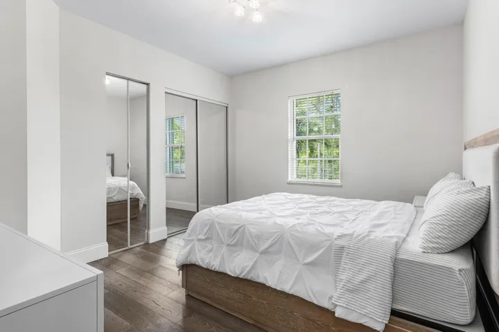 Wood-finish flooring, mirrored sliding closet doors, and a window with natural light
