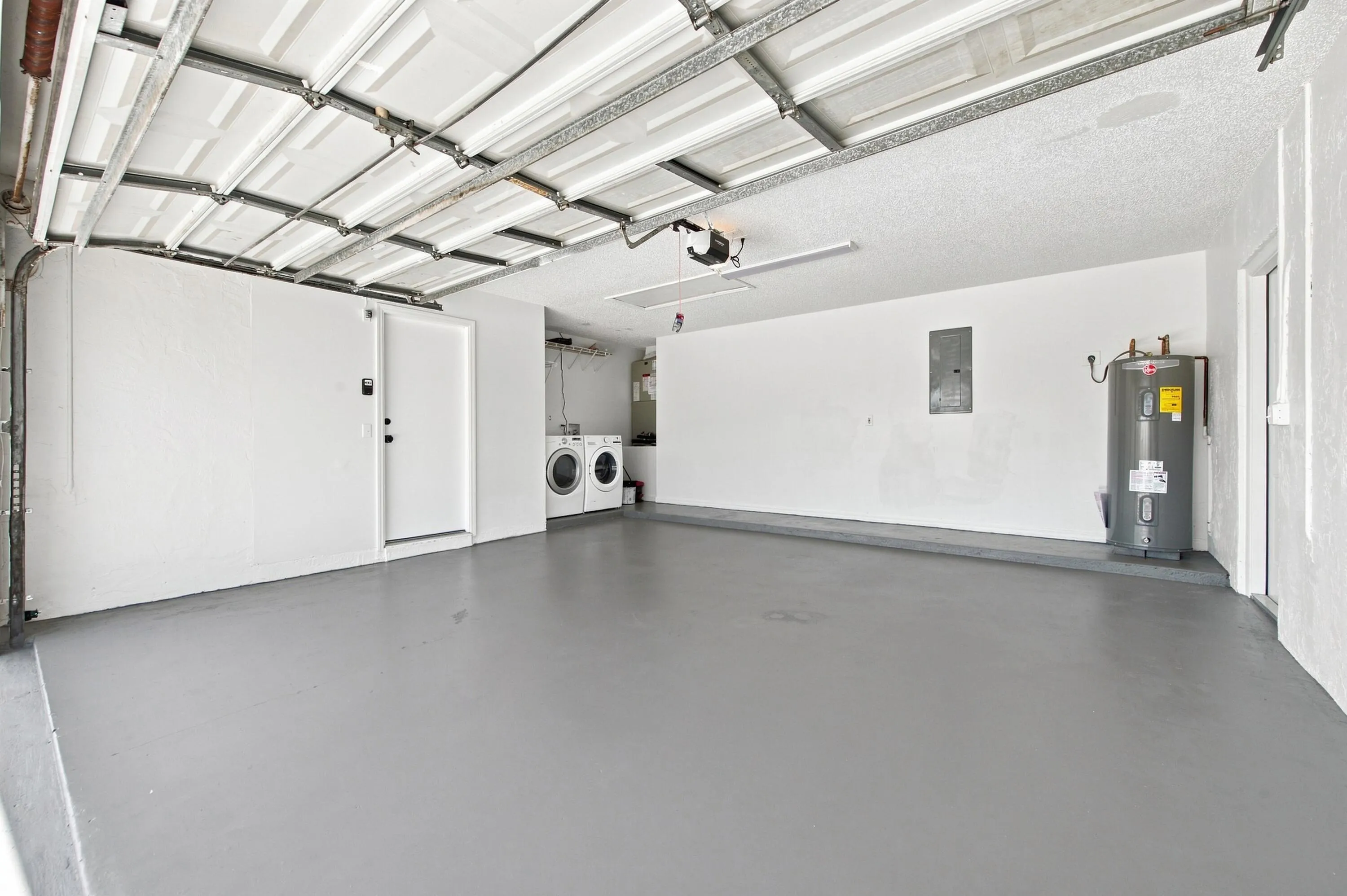 Spacious garage with light gray flooring and a white overhead garage door