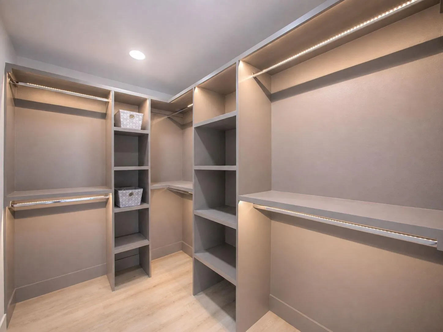 Walk-in closet featuring built-in shelving, hanging rods, recessed ceiling lighting, and integrated strip lighting