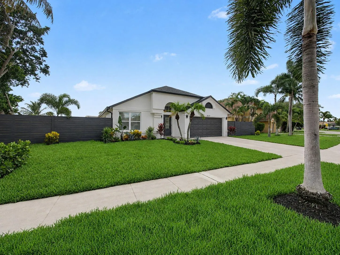 Stucco exterior with a dark roof, a two-car garage, and a concrete driveway