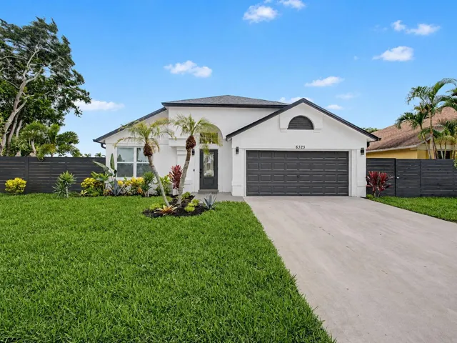 Stucco exterior with a dark shingle roof, a two-car garage, and a concrete driveway