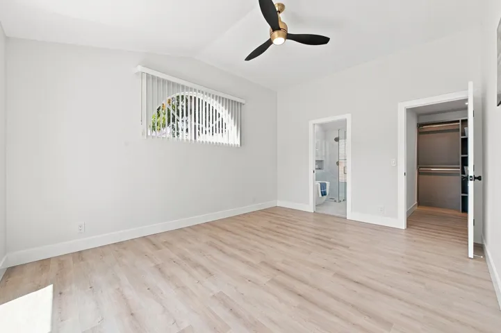 Vaulted ceiling with a brass-finish ceiling fan, wood-finish flooring, and white wall finishes