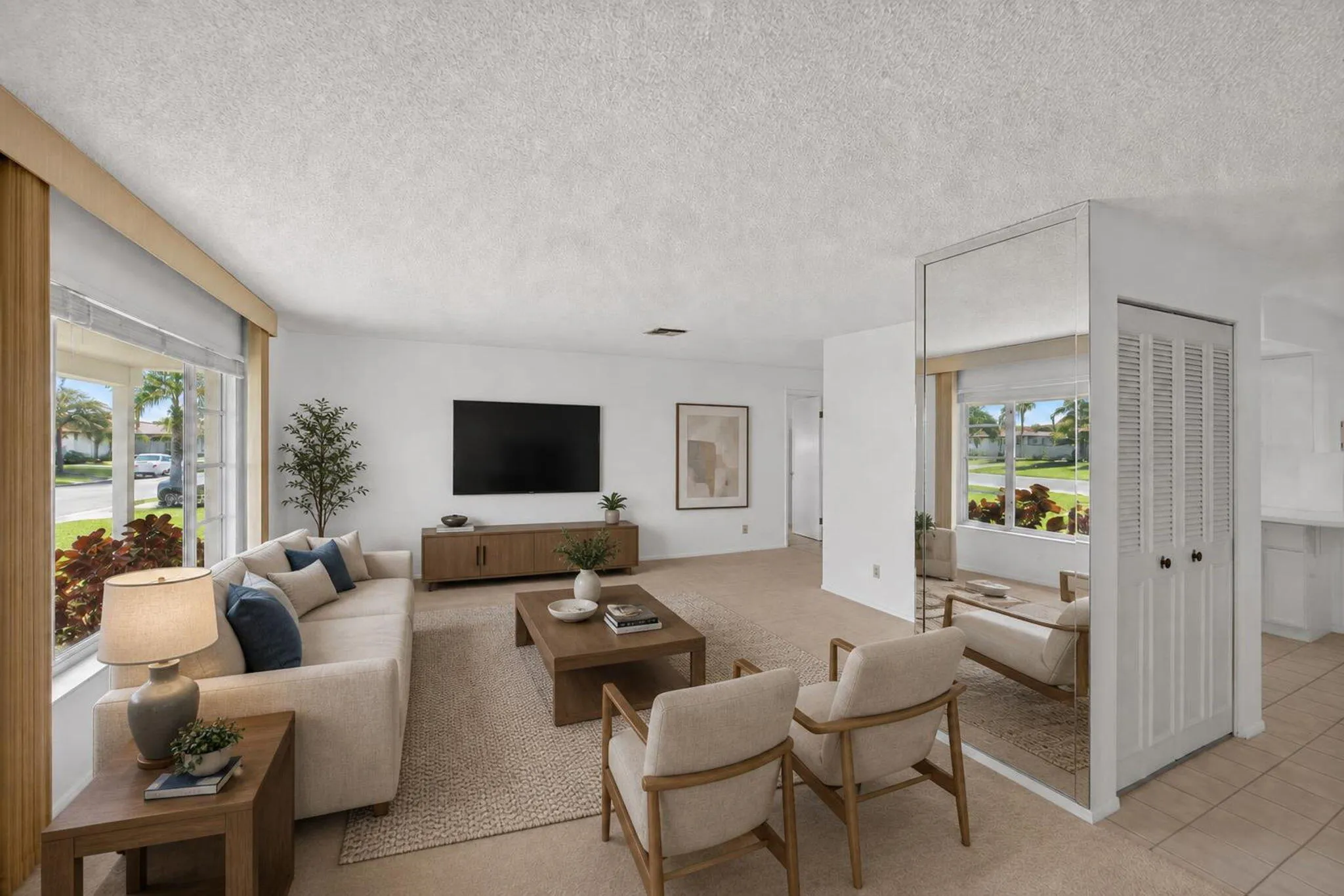 Expansive living area featuring large windows, neutral carpeting, and a mirrored accent wall