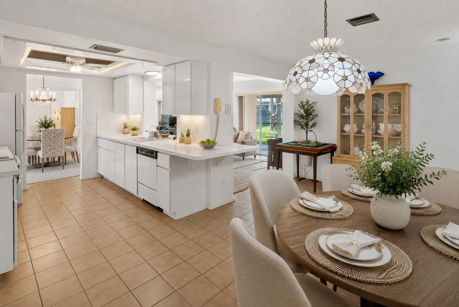 Kitchen featuring white cabinetry, light-colored countertops, tile flooring, and a built-in dishwasher