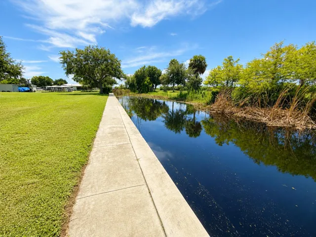 Sunlit Walkway Beside Reflective Canal
