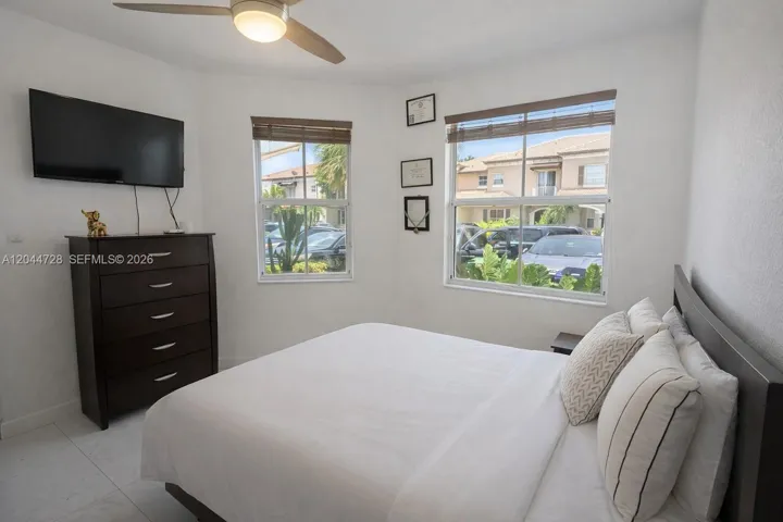 Bright bedroom with clean tile flooring, clean layout, and modern ceiling fan. Well-kept space with natural light.
