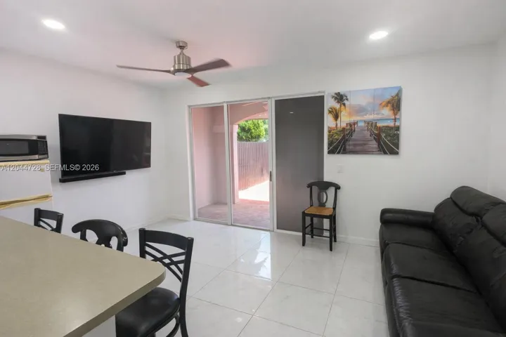 Bright living area with clean tile flooring, and large sliding doors that open to the patio. Functional layout with ceiling fan, and comfortable seating.