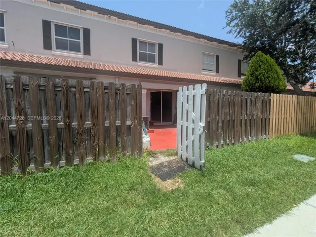 Fenced backyard with red concrete patio and direct access to the home. Clean outdoor space with open lawn and private enclosure.
