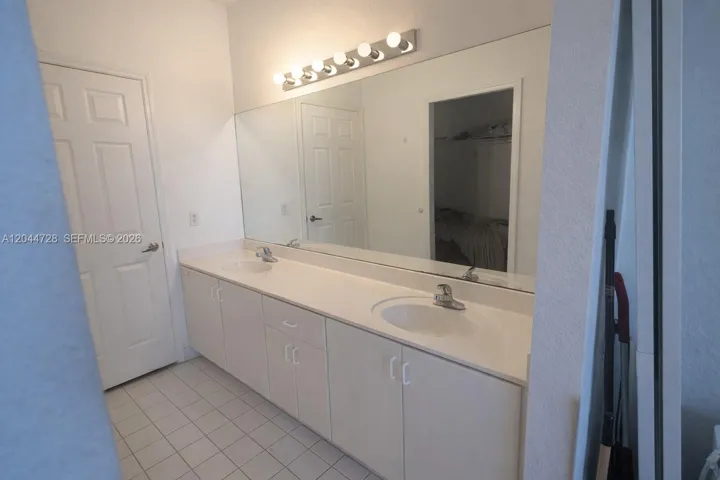 1st Master Bathroom with double-sink vanity, large mirror, and ample storage. Clean tile flooring and practical layout with great natural flow.