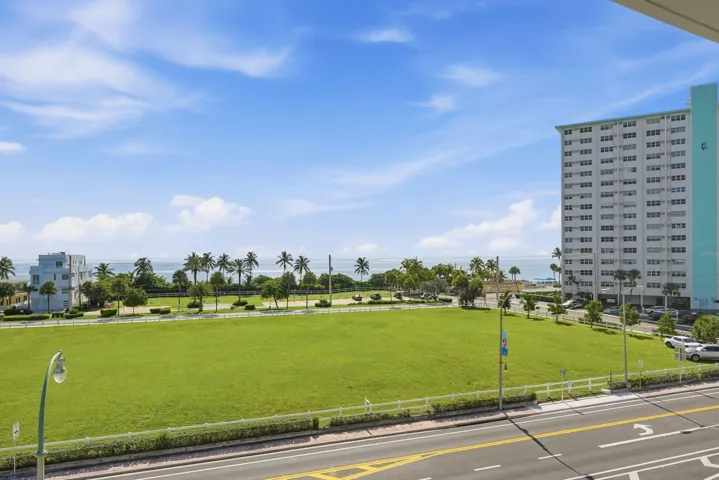 Expansive green space bordered by palm trees and ocean