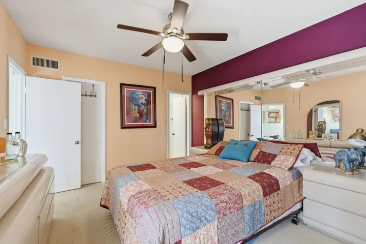 Ceiling fan with integrated lighting, wall-to-wall carpeting, mirrored wall accents, built-in shelving, and white interior doors