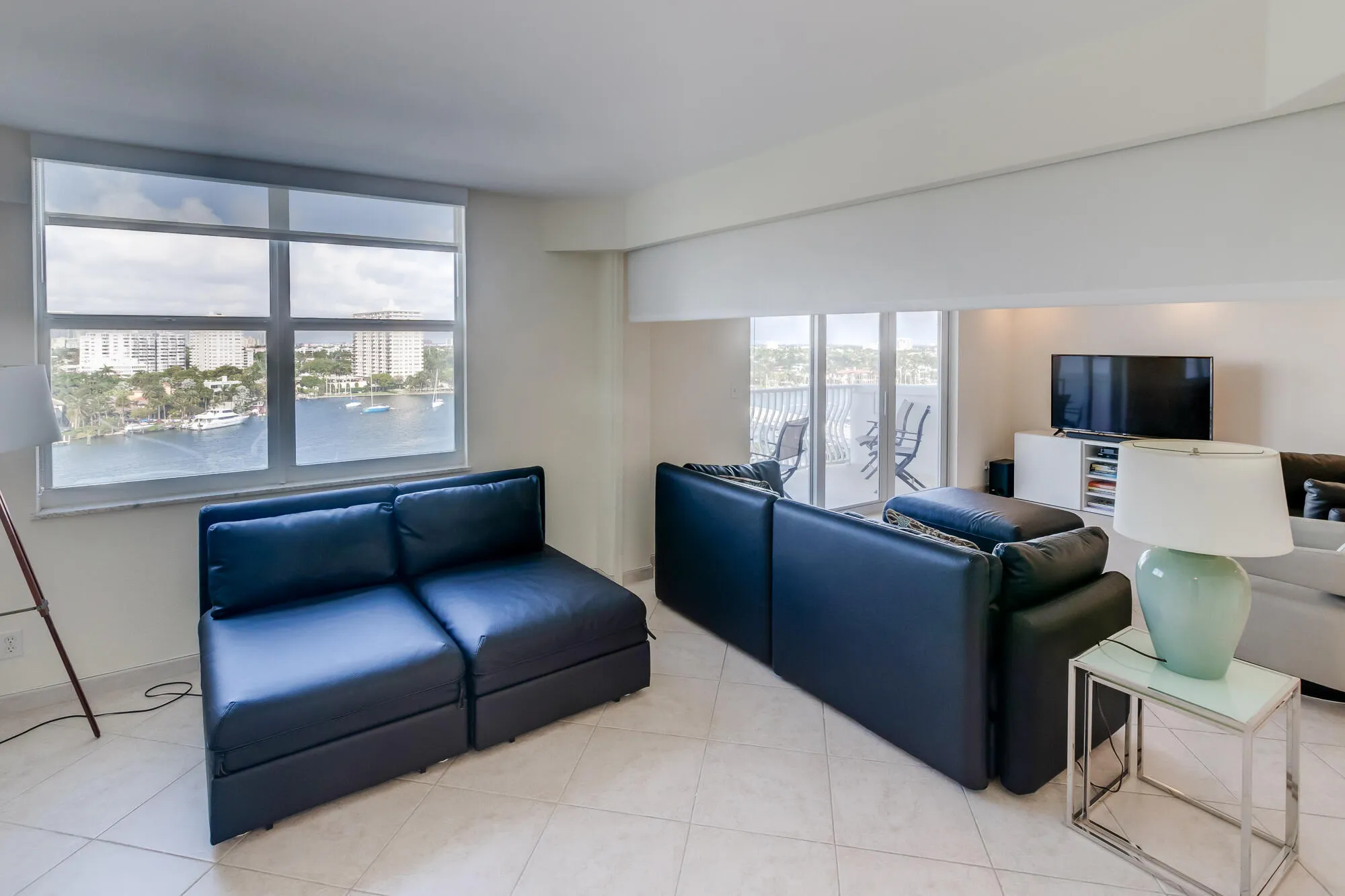 Tiled flooring throughout this space with a large window and a sliding glass door leading to the outdoor balcony