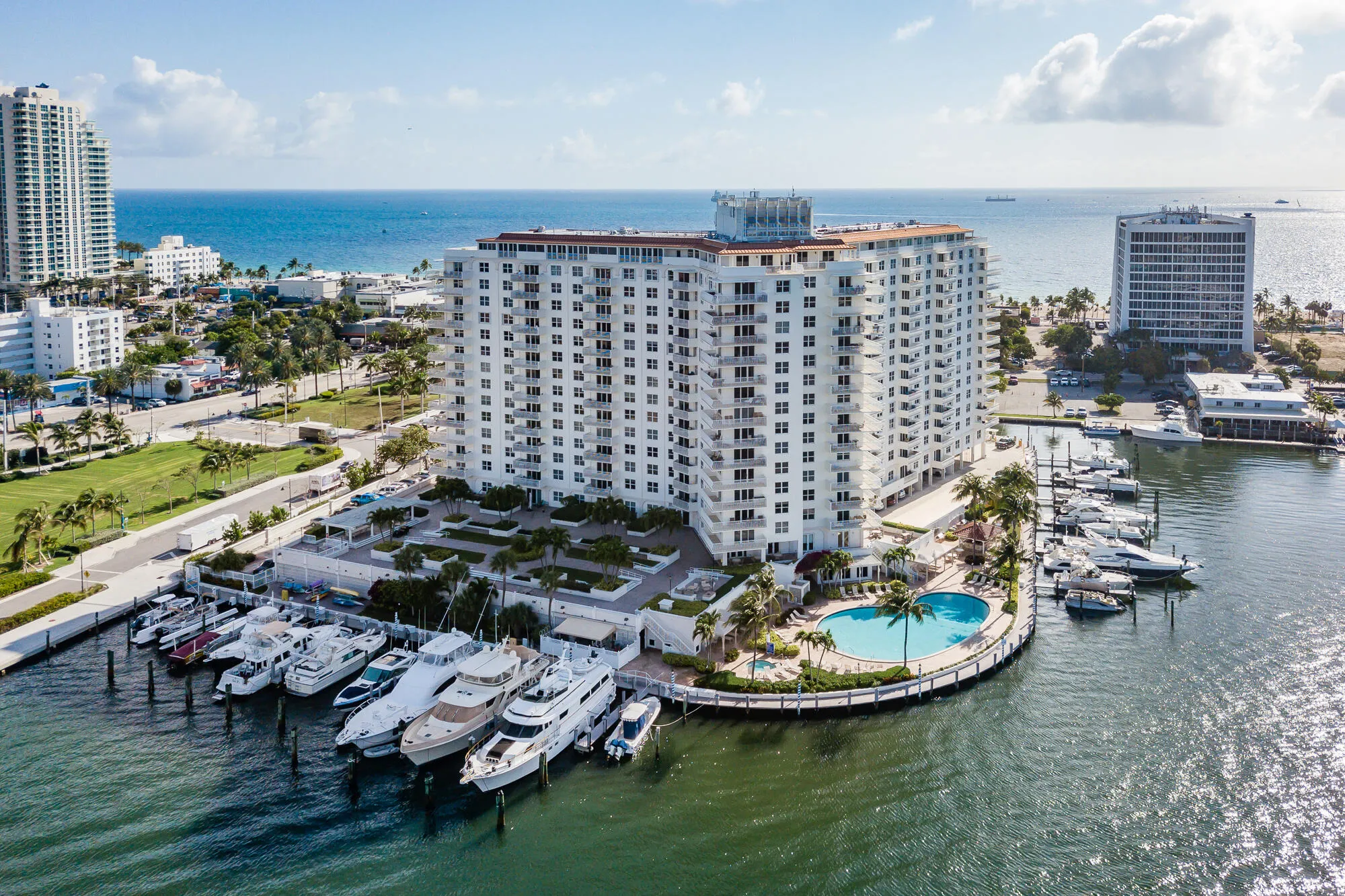 Multi-story building featuring balconies, ground-level swimming pool, and a private marina with multiple boat slips